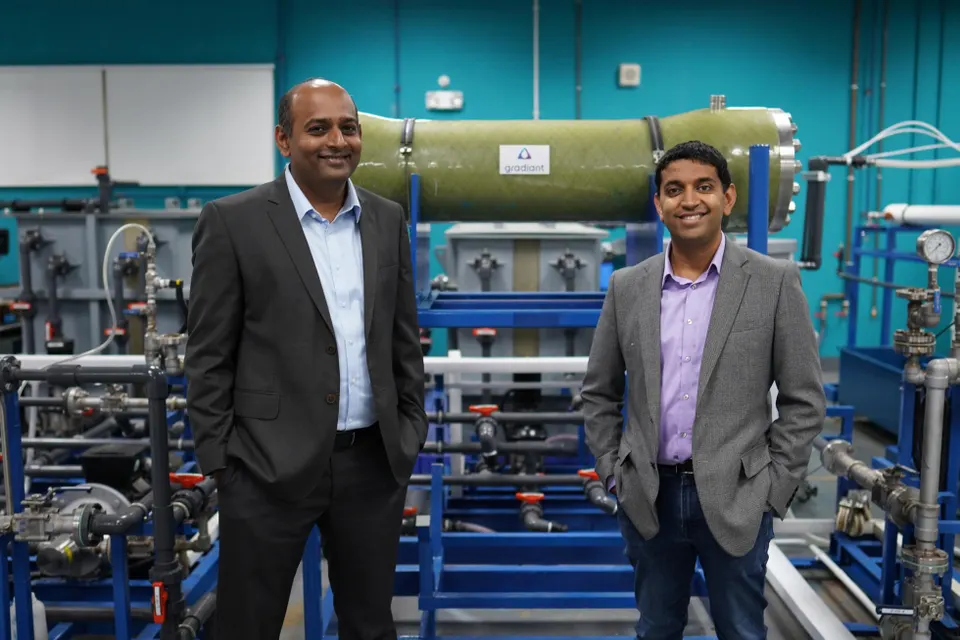 Two men stand in front of industrial equipment