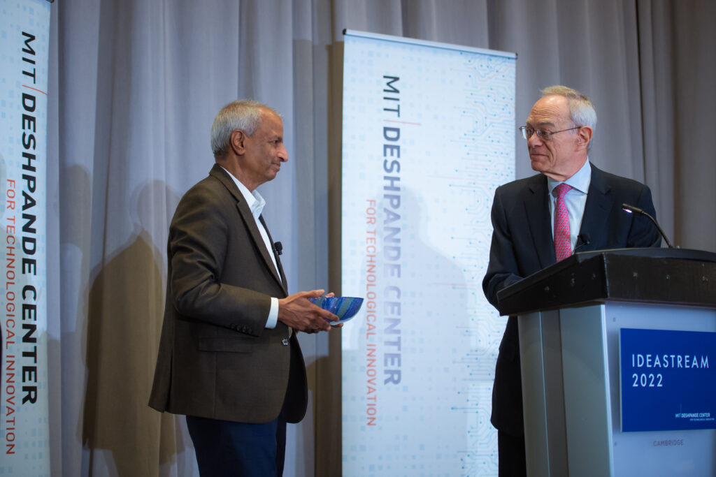 Desh Deshpande holds a decorative glass bowl as Rafael Reif addresses him.